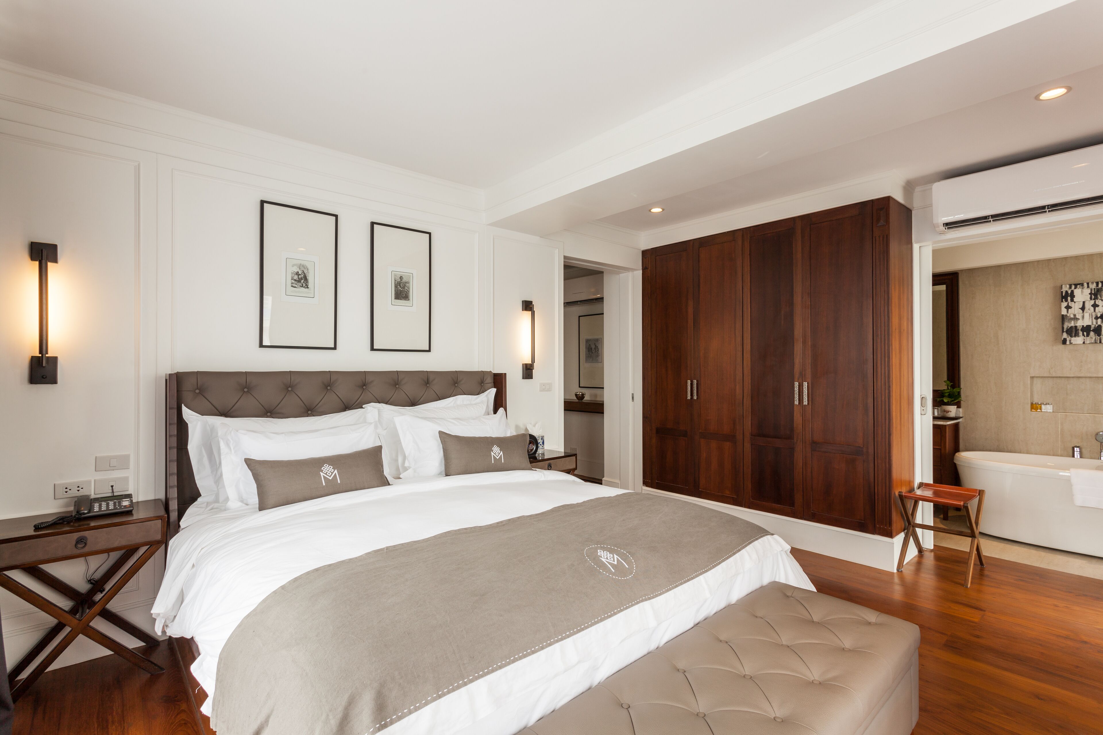 A modern bedroom with a large bed, wooden wardrobe, and a bathroom visible through an open door.