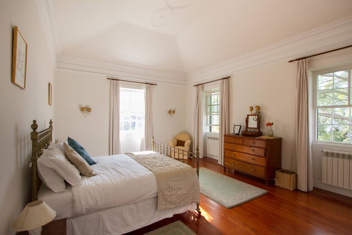 A bedroom with a bed, dresser, chair, and window.