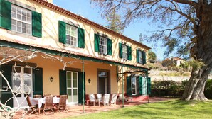 A two-story building with a patio area featuring outdoor seating and a table. - Quinta das Malvas (Funchal)