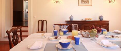 A dining table set for breakfast with various dishes, a fruit bowl, and a pitcher of orange juice.
