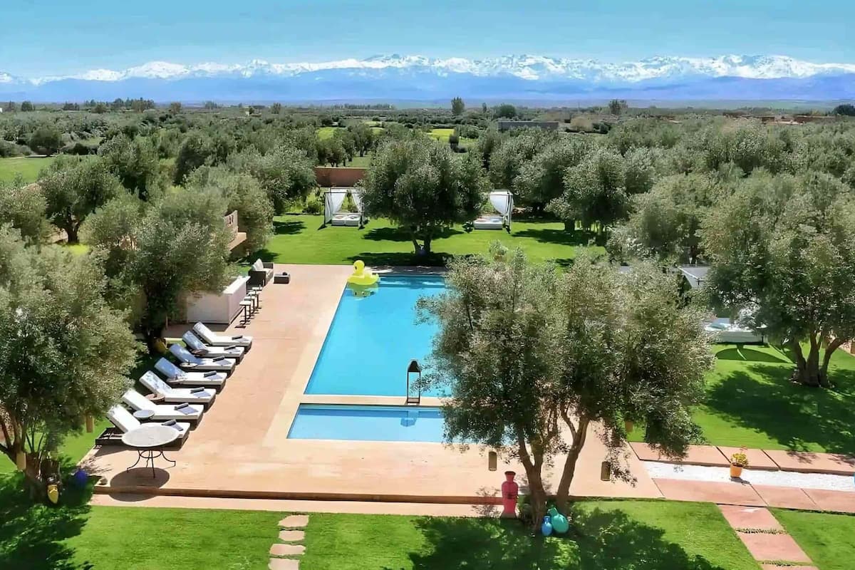 A pool area with lounge chairs and a view of snow-capped mountains.