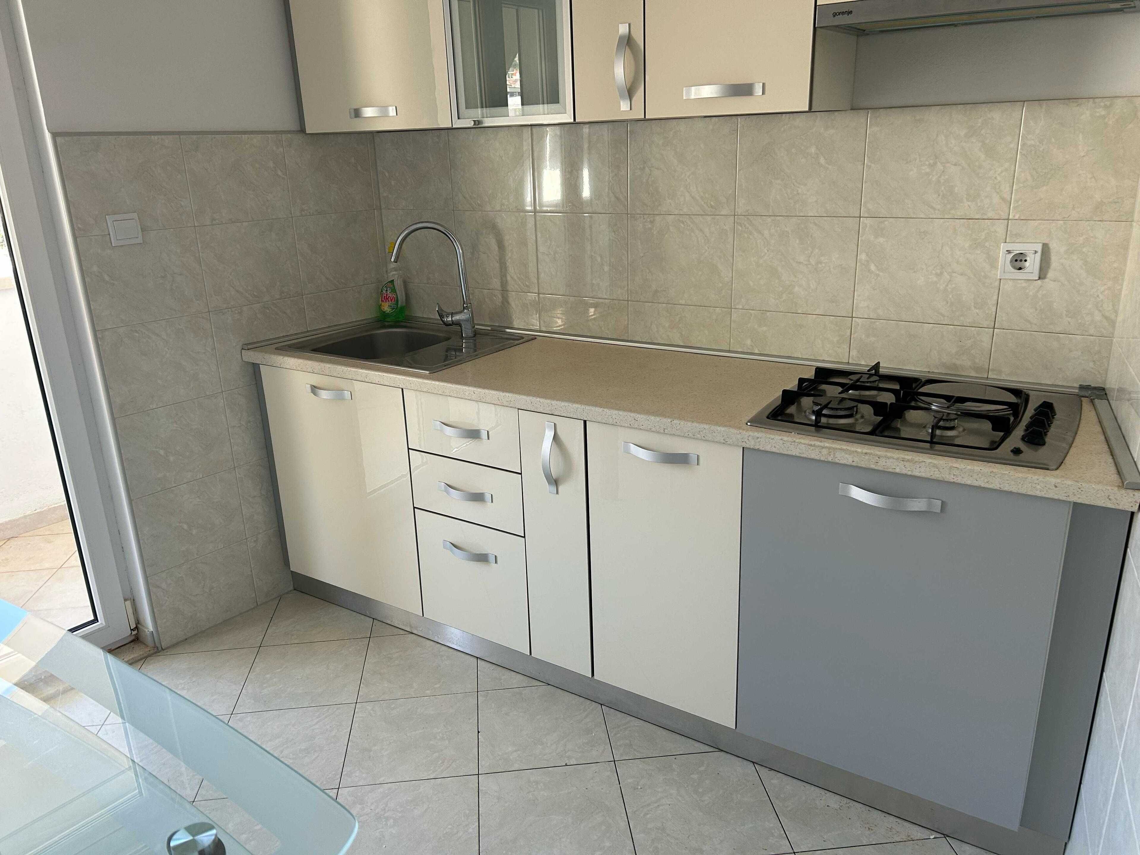A kitchen with a gas stove, a sink, and cabinets.