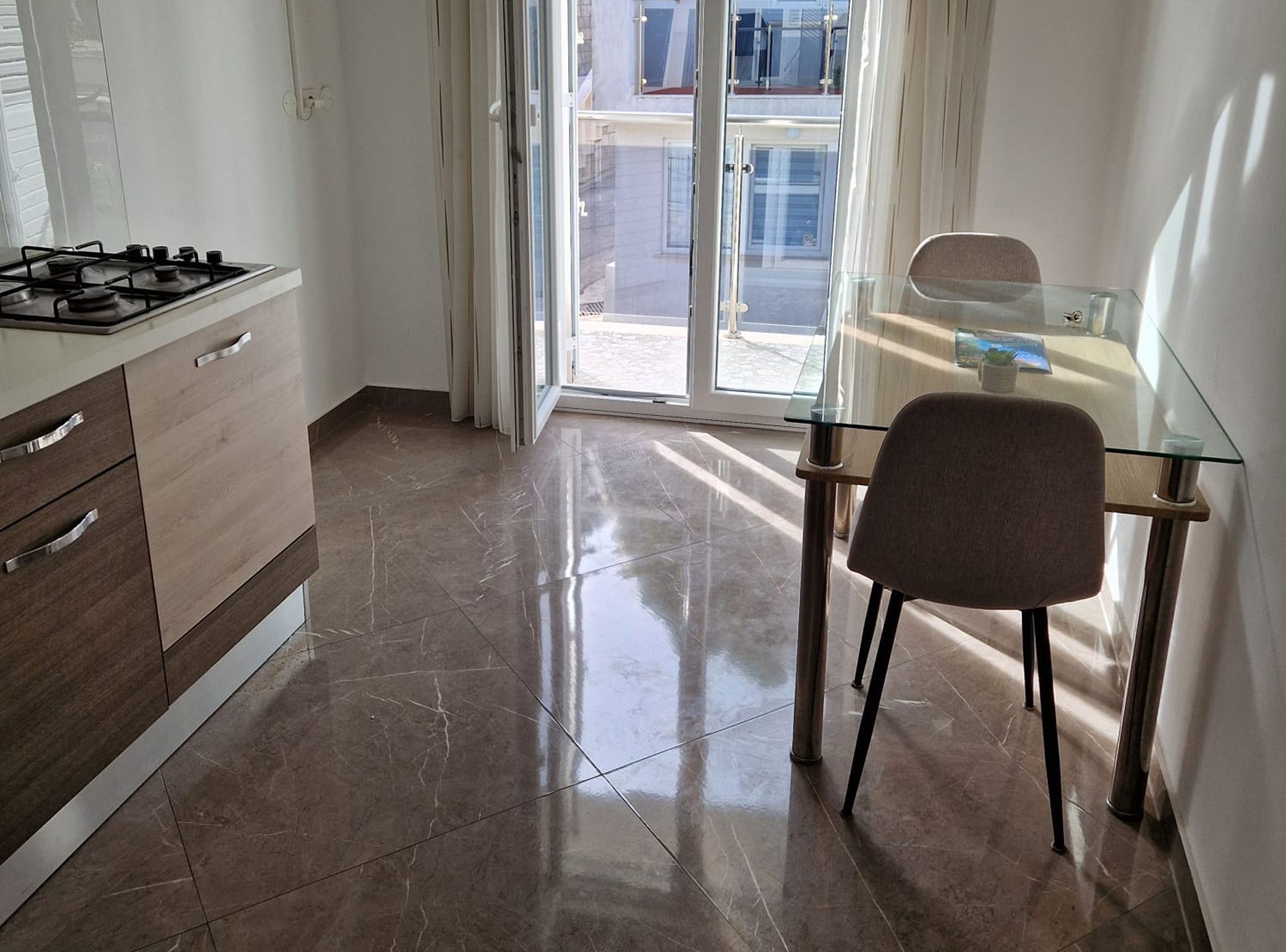 Una cocina moderna con estufa a gas, una mesa de comedor de vidrio y una silla.