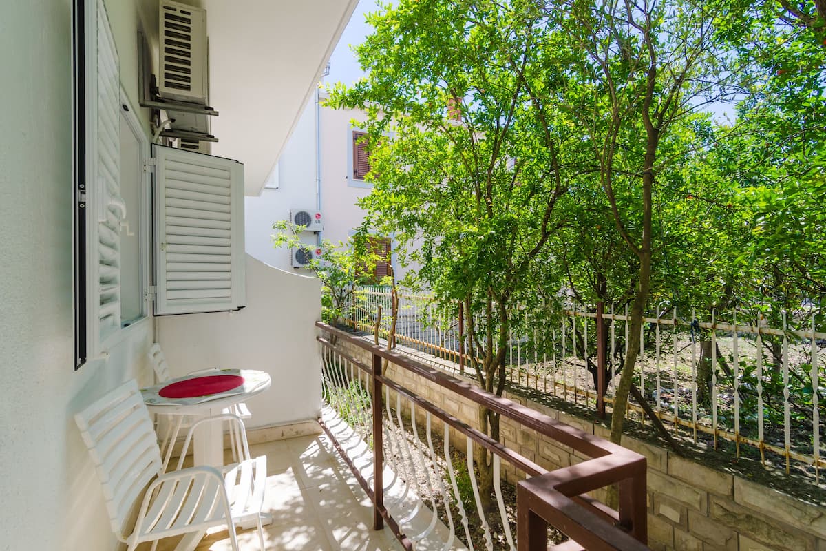 Un balcon avec une chaise blanche, une petite table et une balustrade en bois.
