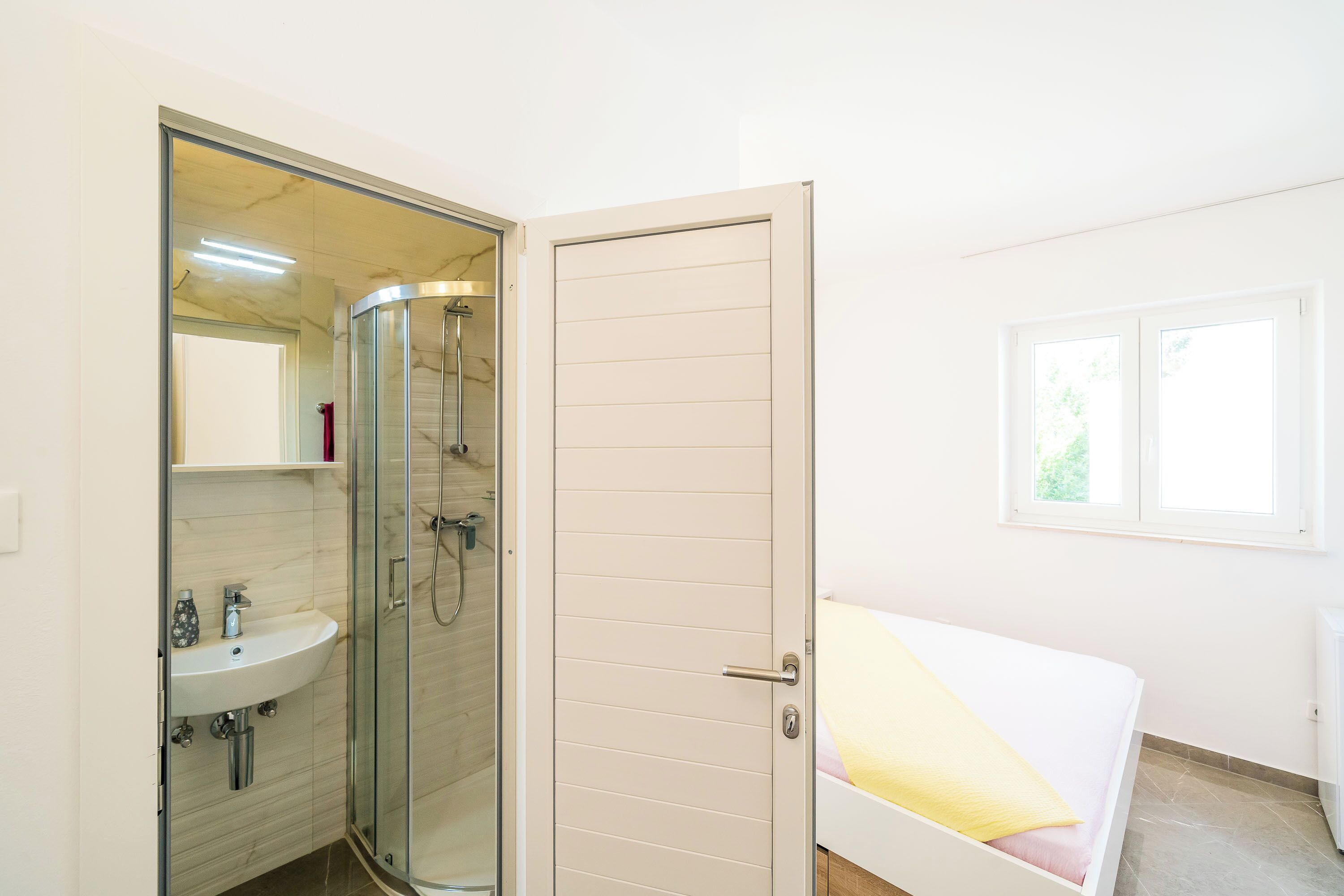 A bathroom with a glass shower enclosure, a sink, and a toilet.