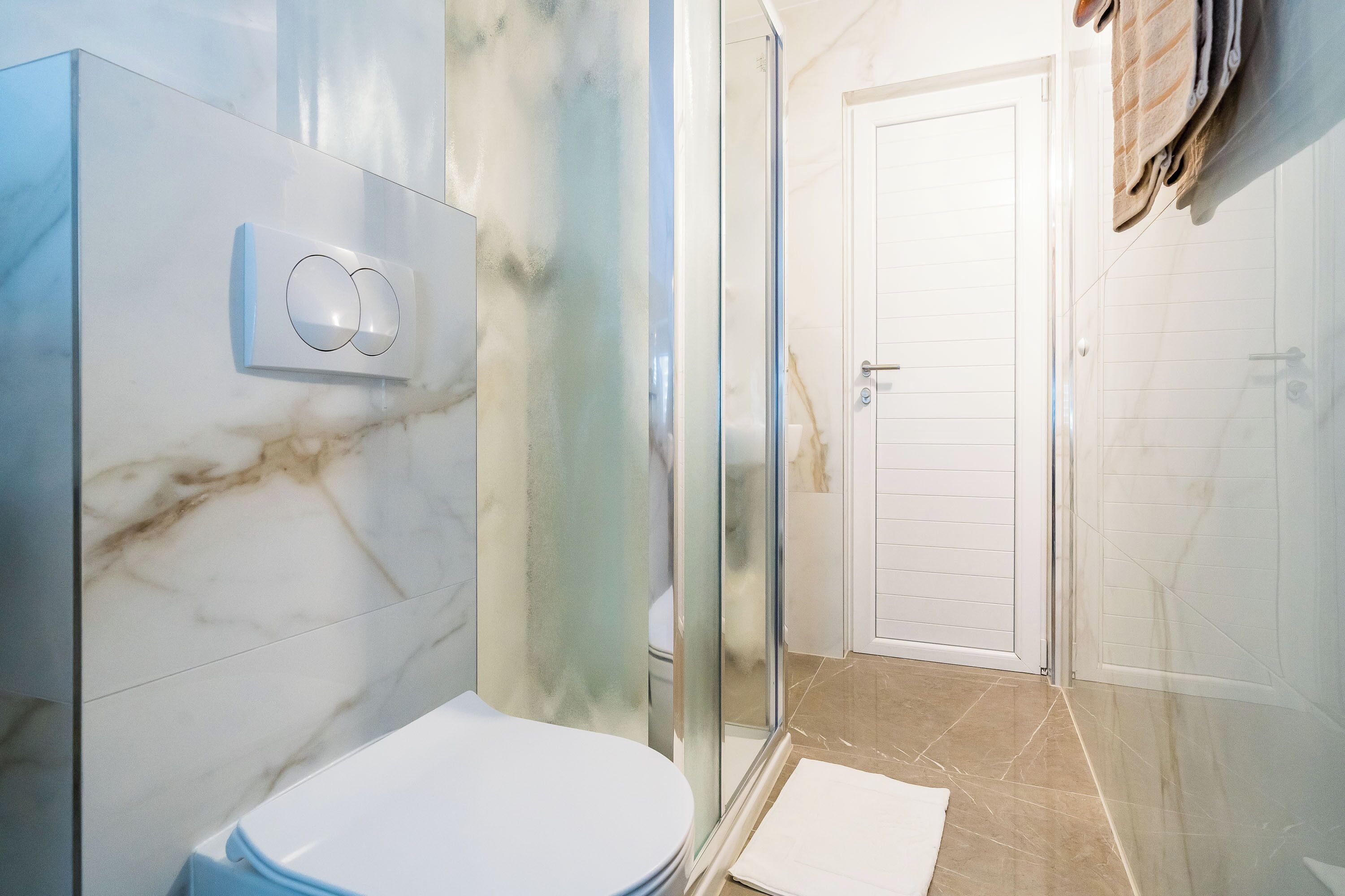 Un baño con cabina de ducha de vidrio, inodoro y puerta blanca.