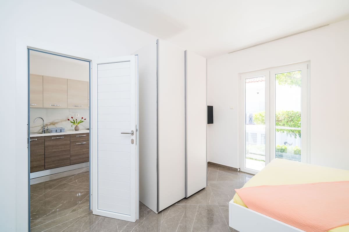 Une chambre moderne avec un lit, une porte coulissante donnant sur une salle de bain et une vue sur l’extérieur grâce à une grande fenêtre.