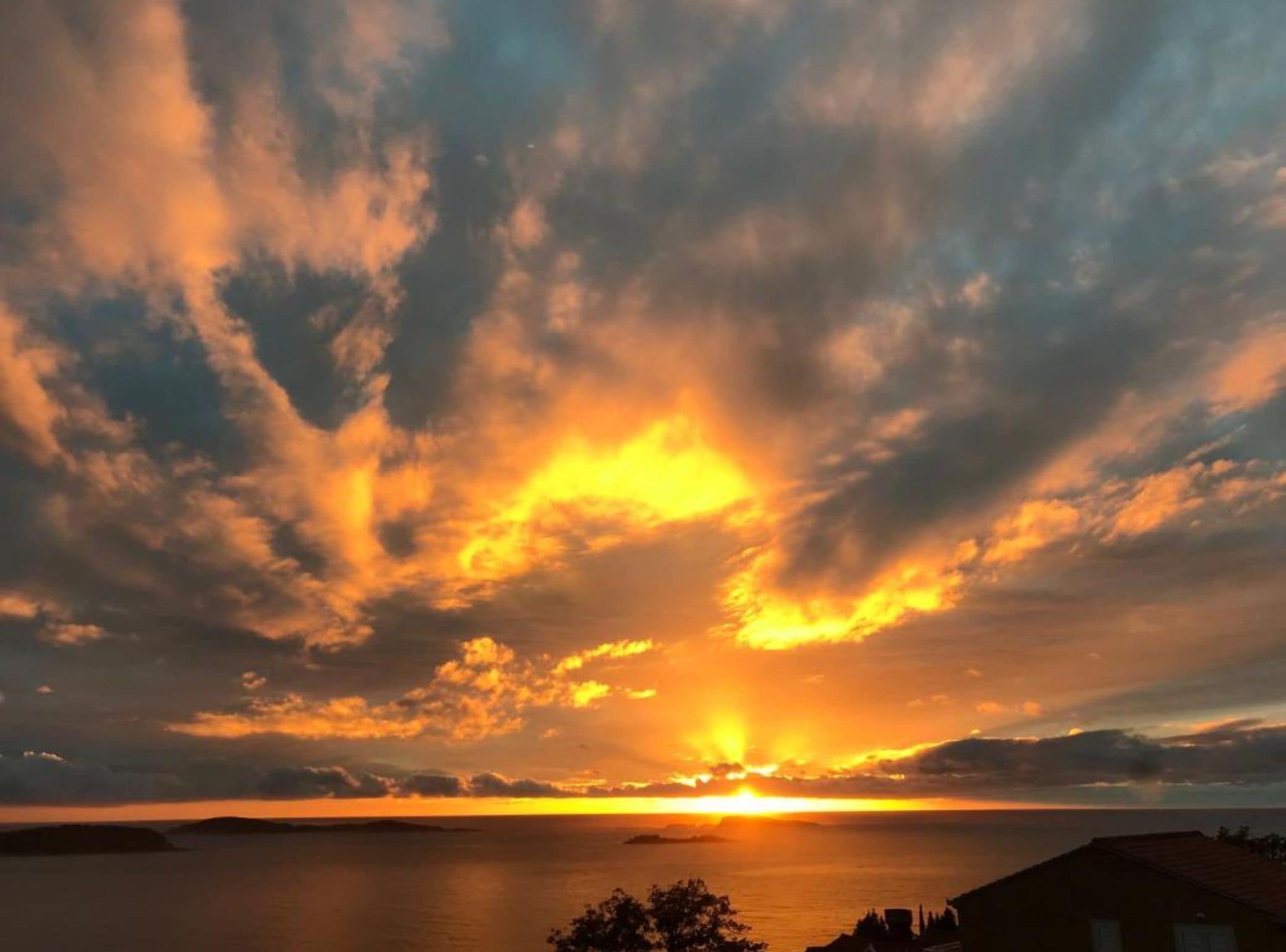 A sunset over a body of water with a distant shoreline.
