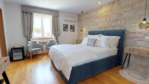 A bedroom with a large bed, a stone wall, a desk, and a chair. - Riva and Diocletian Apartments (Split)