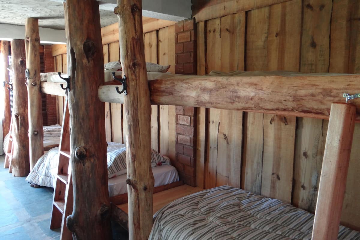 Une chambre rustique avec des lits superposés en bois et un mur en briques.