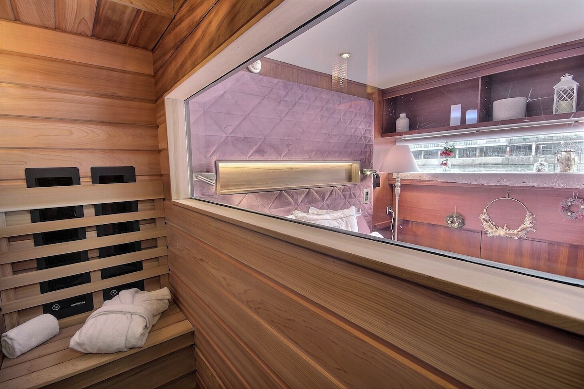 Eine Holzsauna mit Glasabschluss, einer Sitzbank und Handtüchern.