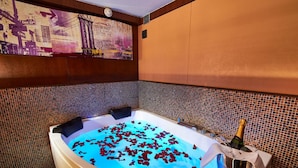 A bathtub filled with water and rose petals, a bottle of champagne, and a clock on the wall. - VIP Paris Yacht Hotel (Paris)