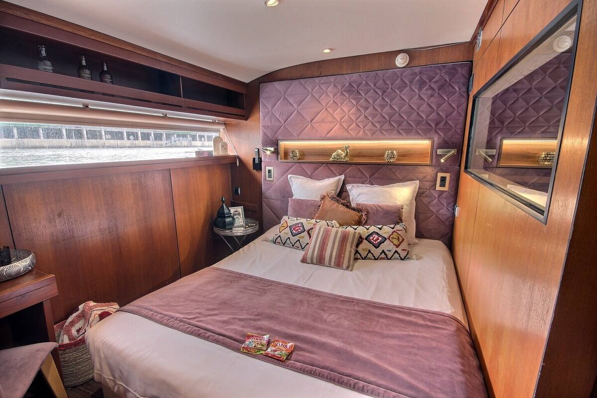 Ein gemütliches Schlafzimmer mit Bett, Kissen, einem Nachttisch und einem Fenster.