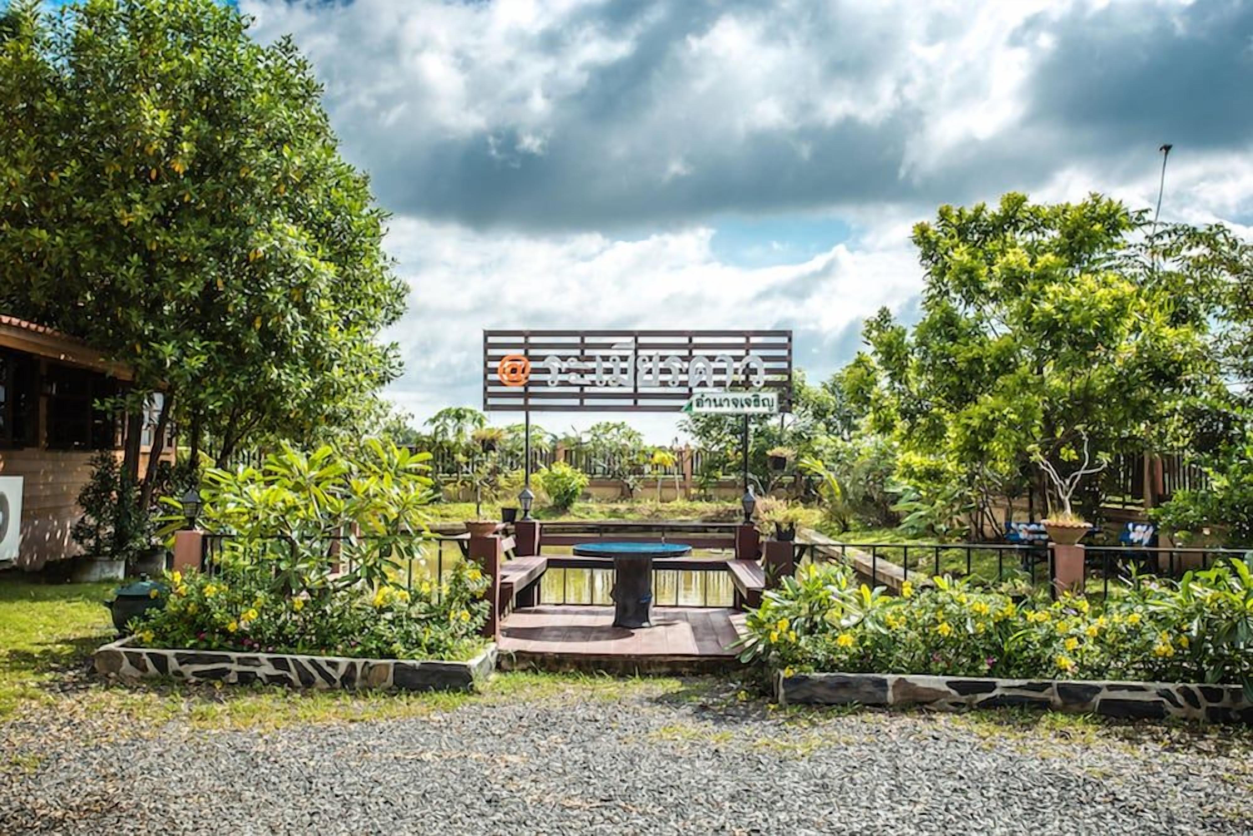 A garden with a table and benches, surrounded by trees and a signboard.