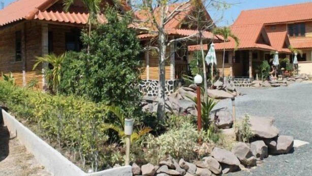 Edifici amb teulada ceràmica, envoltat de vegetació i roques.