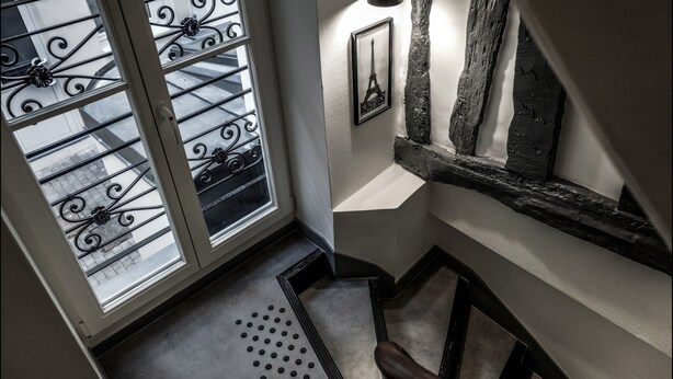 A staircase with a black metal railing, a picture of the Eiffel Tower, and a textured wall. - Hôtel Résidence Montebello (Paris)