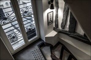 A staircase with a black metal railing, a picture of the Eiffel Tower, and a textured wall. - Hôtel Résidence Montebello (Paris)