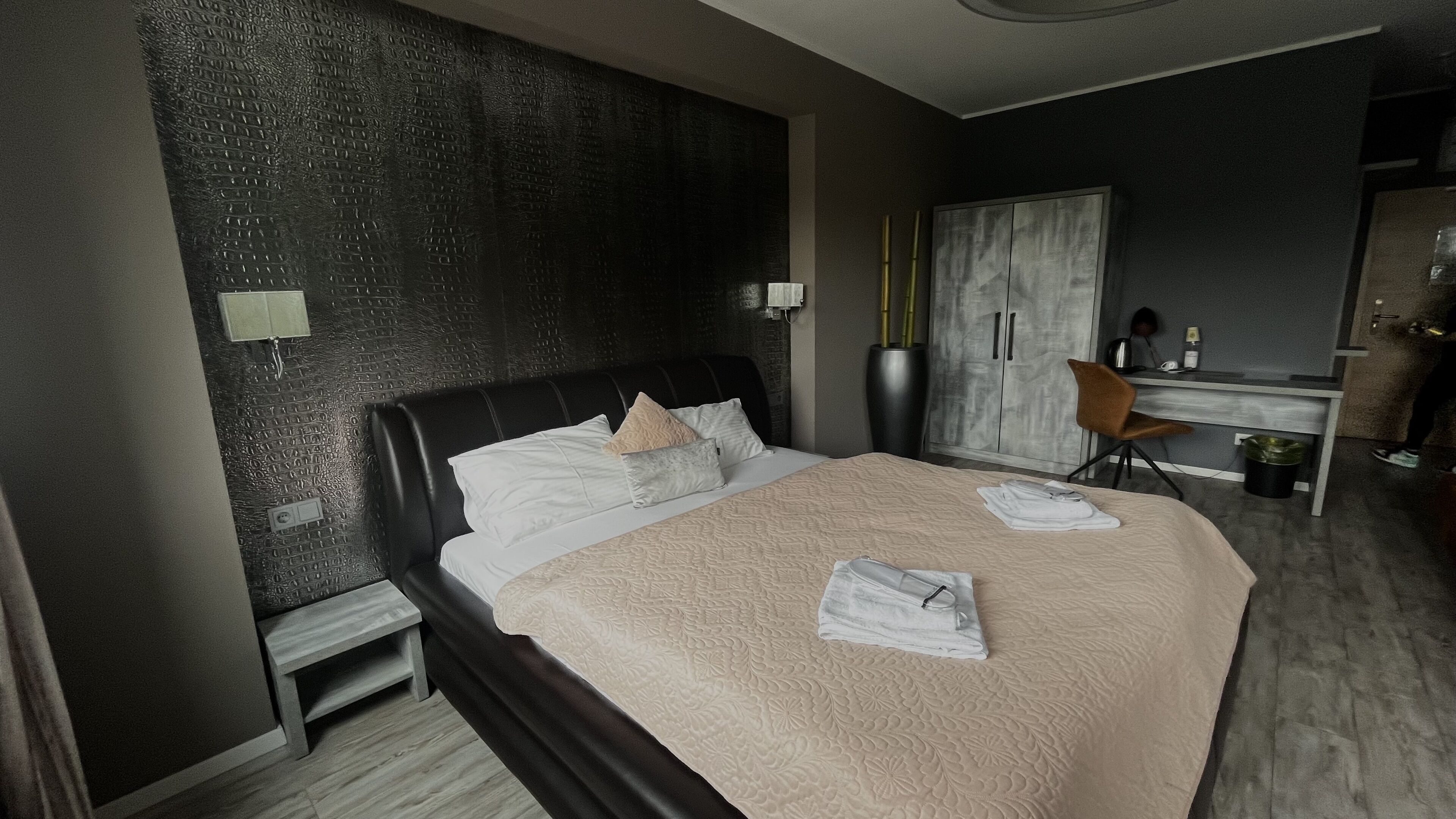 Ein modernes Hotelzimmer mit einem großen Bett, einem Schreibtisch und einem Kleiderschrank.