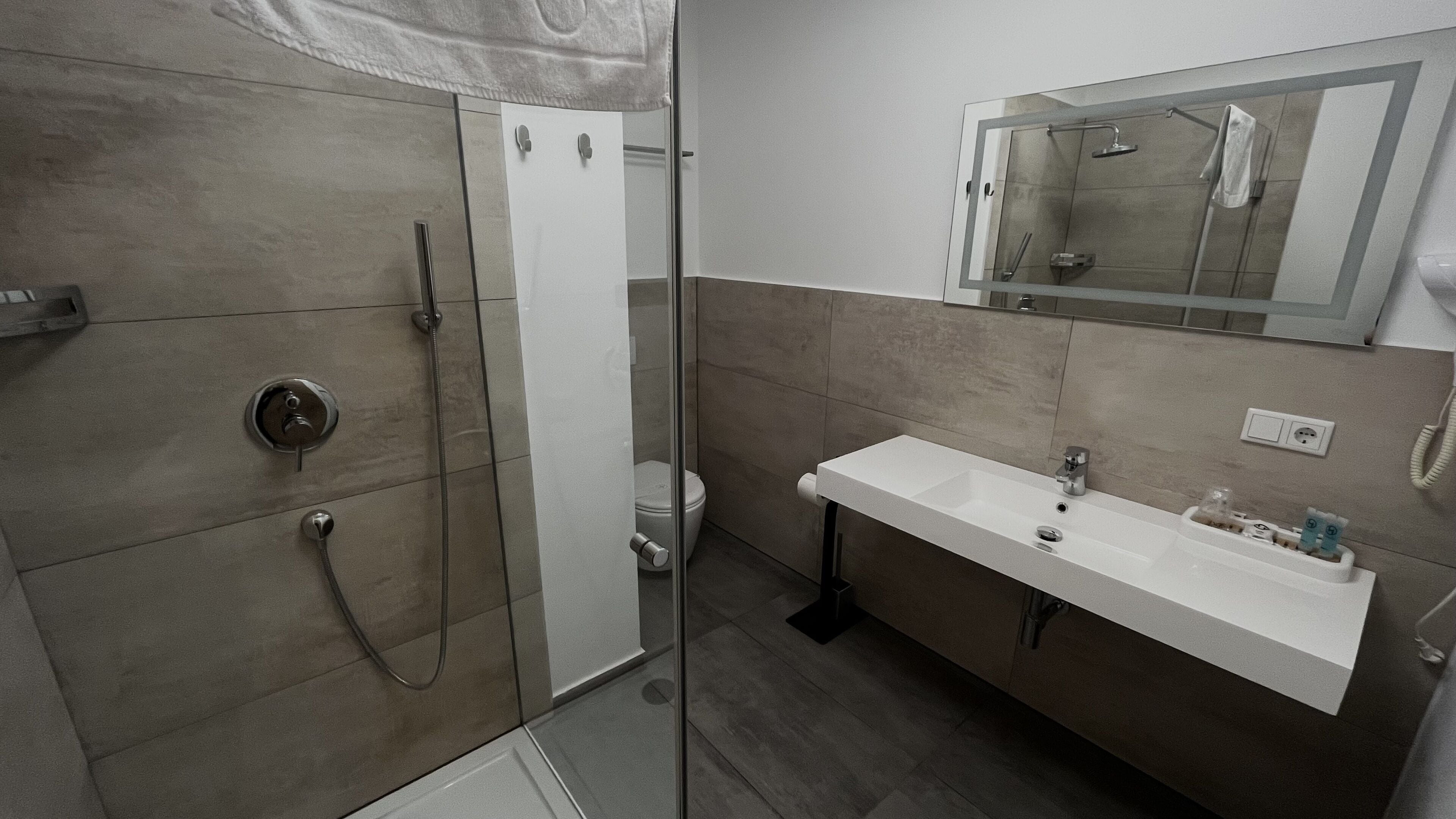 A modern bathroom with a glass-enclosed shower, a white sink, and a mirror above the sink.