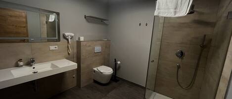 A modern bathroom with a shower, toilet, and sink.