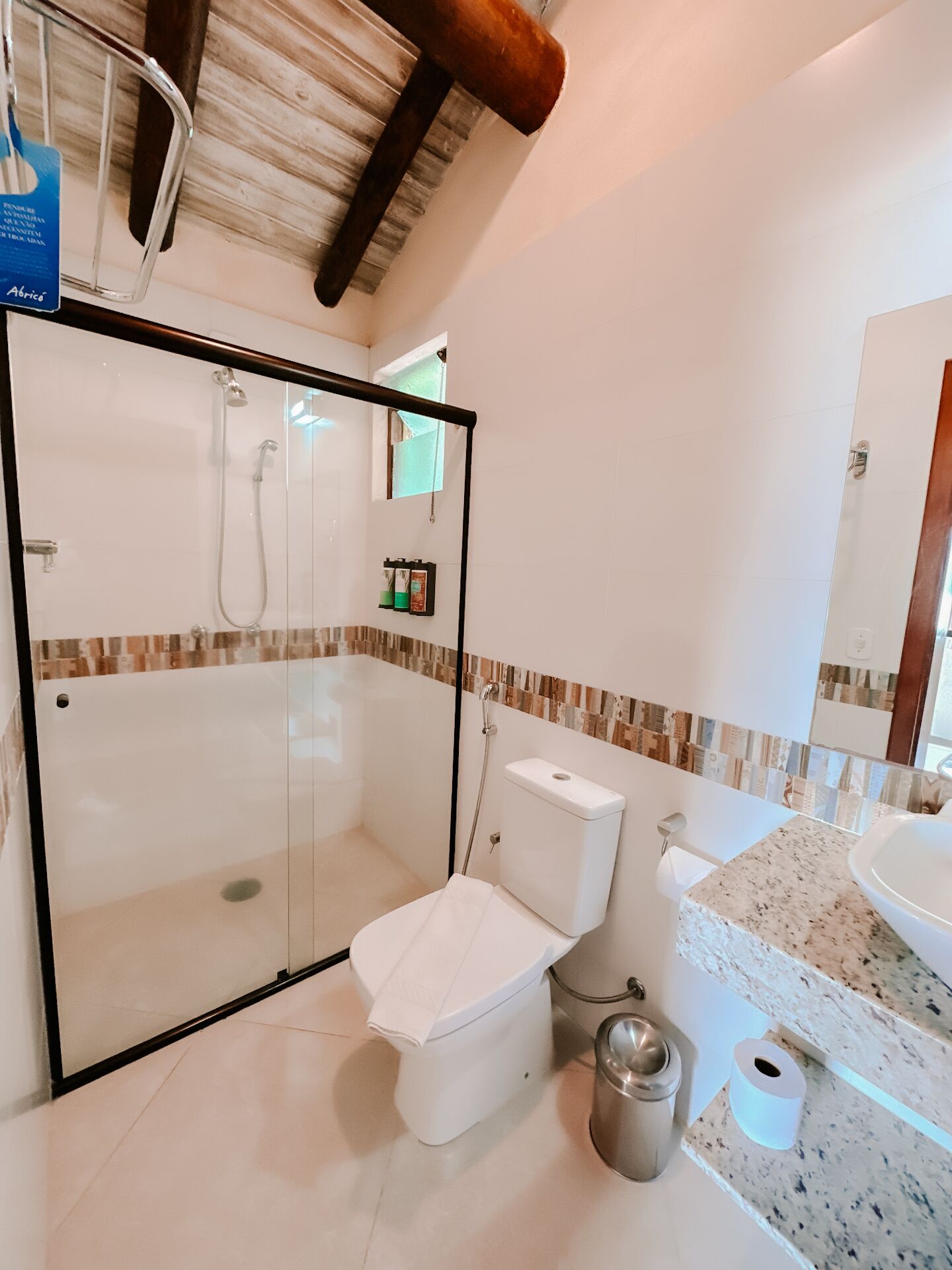 Un baño moderno con ducha de vidrio, inodoro, lavamanos y encimera de mármol.