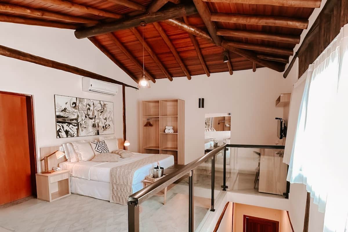 A bedroom with a bed, bedside table, and a wooden ceiling.