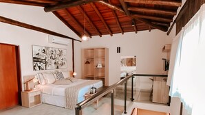 A spacious bedroom with a large bed, a wooden ceiling, a glass staircase, and a view of a balcony. - Abricó Beach Hotel (São Sebastião)