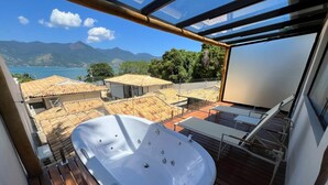 A modern outdoor hot tub on a wooden deck with a view of a mountainous landscape and a body of water. - Abricó Beach Hotel (São Sebastião)