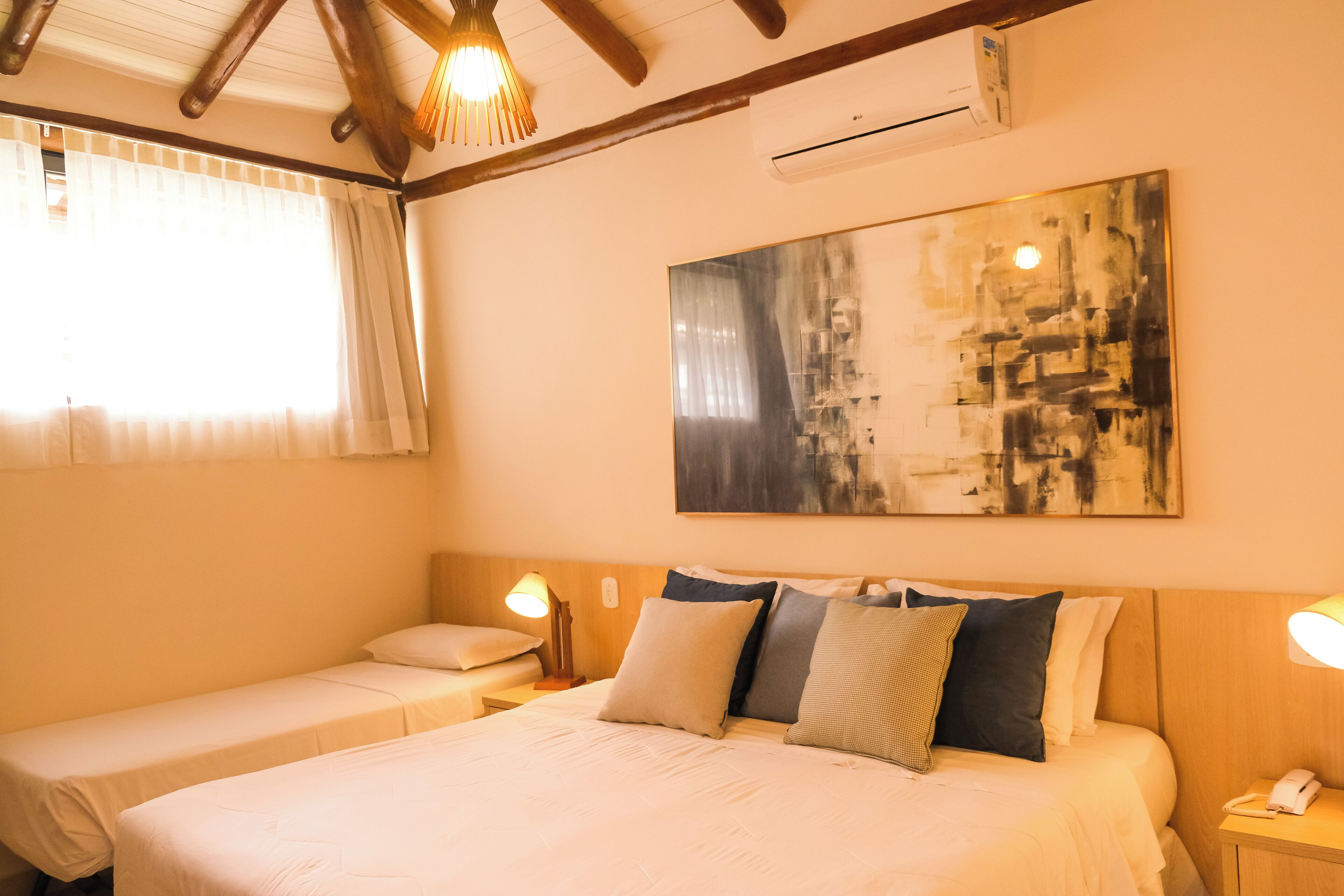 A hotel room with a large bed, two bedside tables, a ceiling fan, and a large abstract painting on the wall.