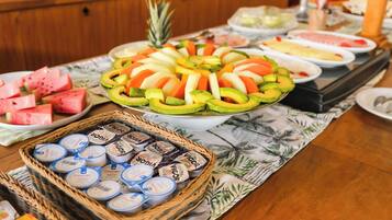 A buffet table with various fruits, a pineapple, and containers of yogurt.