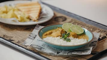 A meal with rice and a curry dish, served on a tray with newspaper.