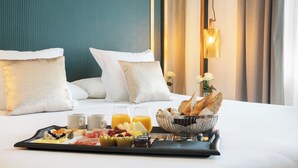 A neatly made bed with white pillows and a tray of breakfast including fruits, bread, and juice. - LA FRANÇA HOTEL BOUTIQUE (Barcelona)
