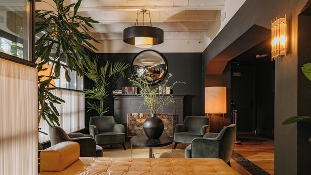 A modern lobby with a sofa, chairs, a round table, a mirror, and a bookshelf. - LA FRANÇA HOTEL BOUTIQUE (Barcelona)