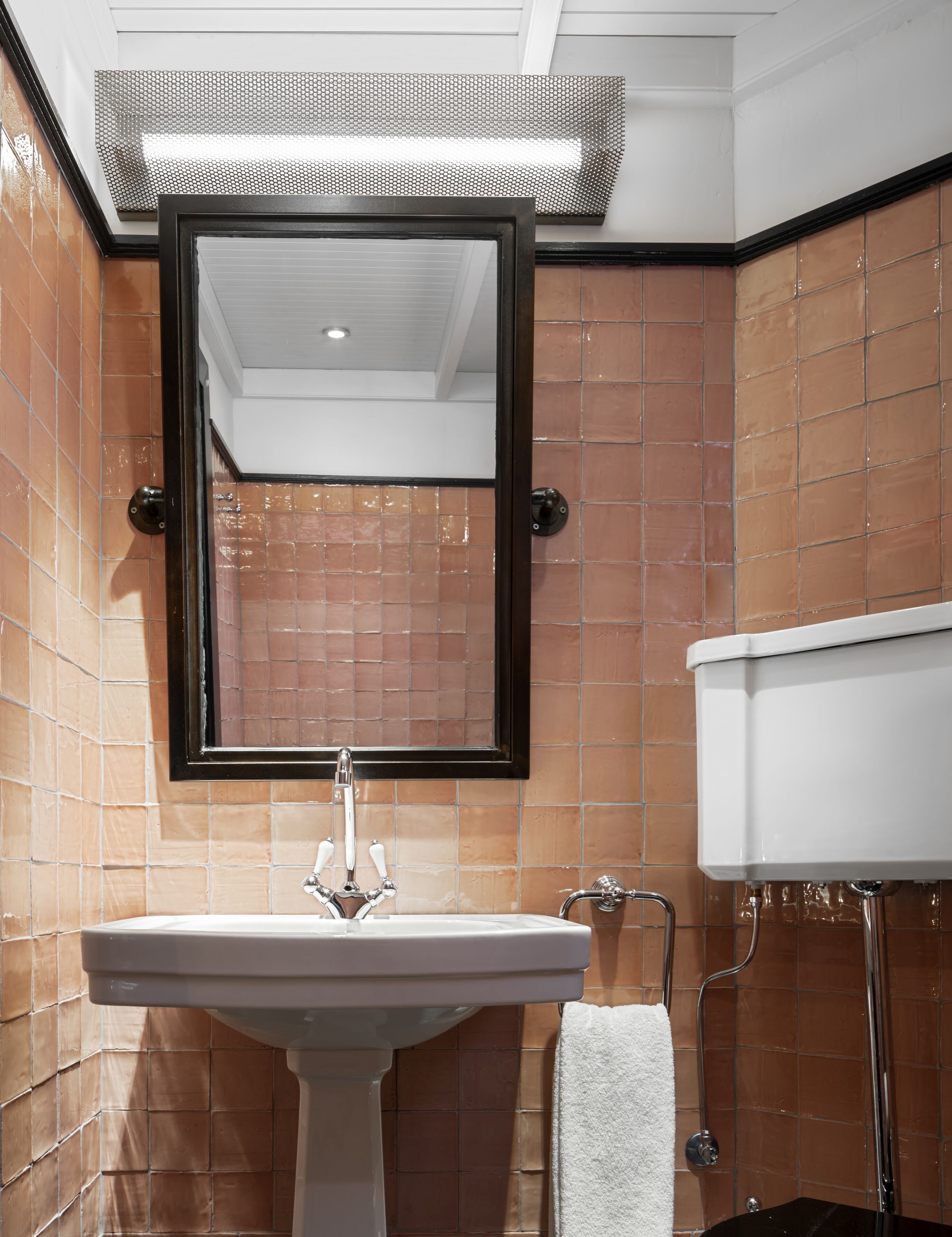 Un baño con un lavamanos blanco, un espejo y un inodoro.