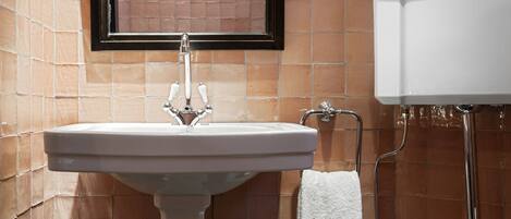 Un baño con un lavamanos blanco, un espejo y un inodoro.