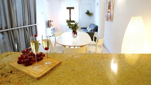 A kitchen with a granite countertop, a dining table with chairs, a vase with green plants, and a painting on the wall. - La Lonja Homes - Turismo de Interior (Palma de Mallorca)