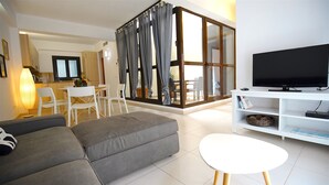 A modern living room with a grey sofa, a white coffee table, and a flat-screen TV on a white TV stand. - La Lonja Homes - Turismo de Interior (Palma de Mallorca)