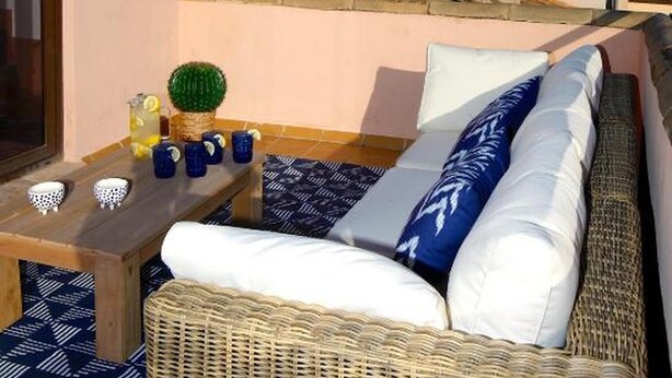 A balcony with wicker furniture, a table with mugs and a pitcher, and a view of a historic building. - La Lonja Homes - Turismo de Interior (Palma de Mallorca)