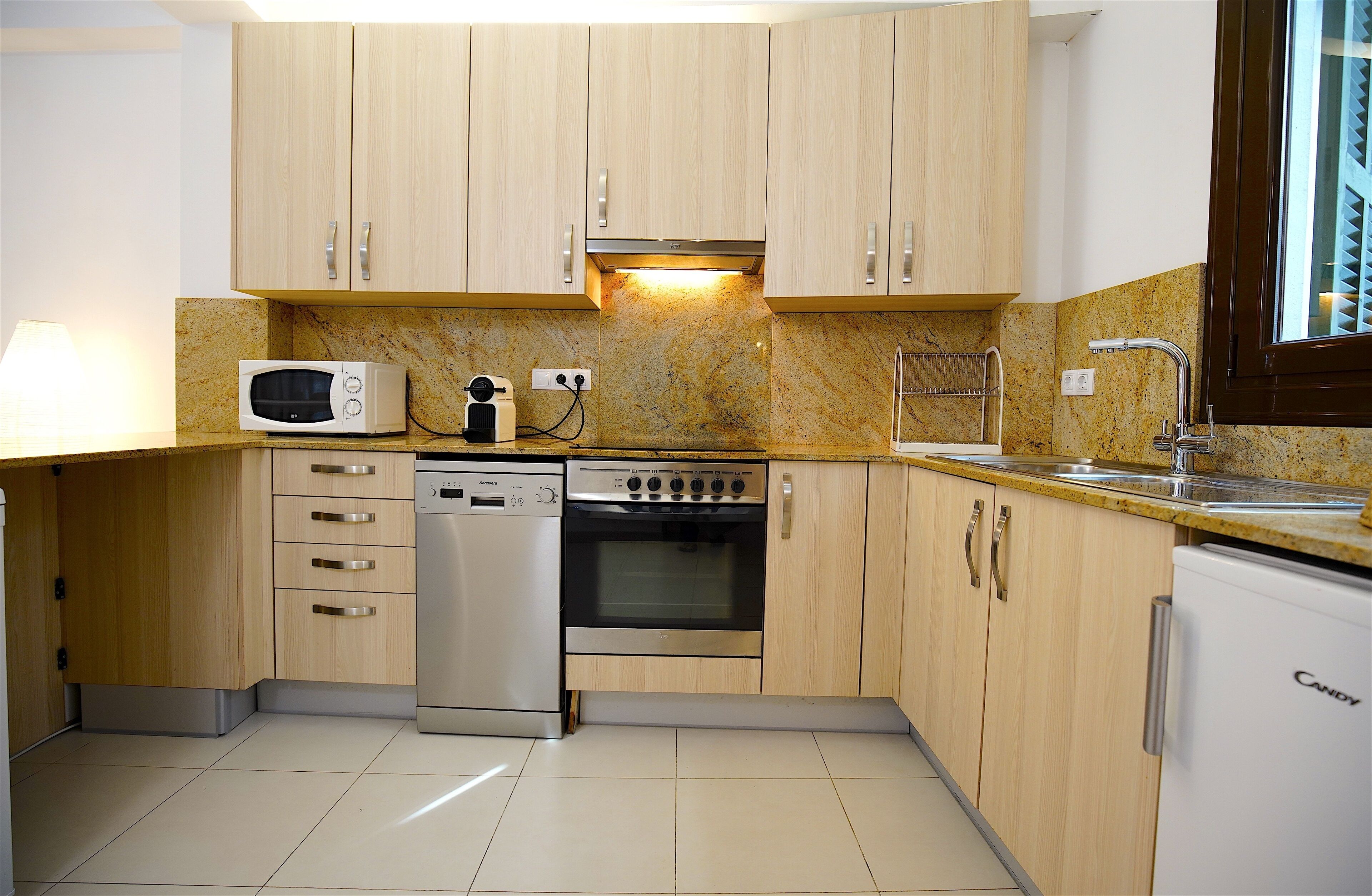 Een moderne keuken met houten kastjes, een ingebouwde magnetron, vaatwasser, oven en een spoelbak.