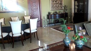 Un coin repas avec une table et des chaises en bois, un lustre et un vase décoratif rempli de fleurs.