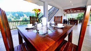 Een eethoek met een houten tafel gedekt voor thee, een trap en uitzicht op het omliggende landschap.