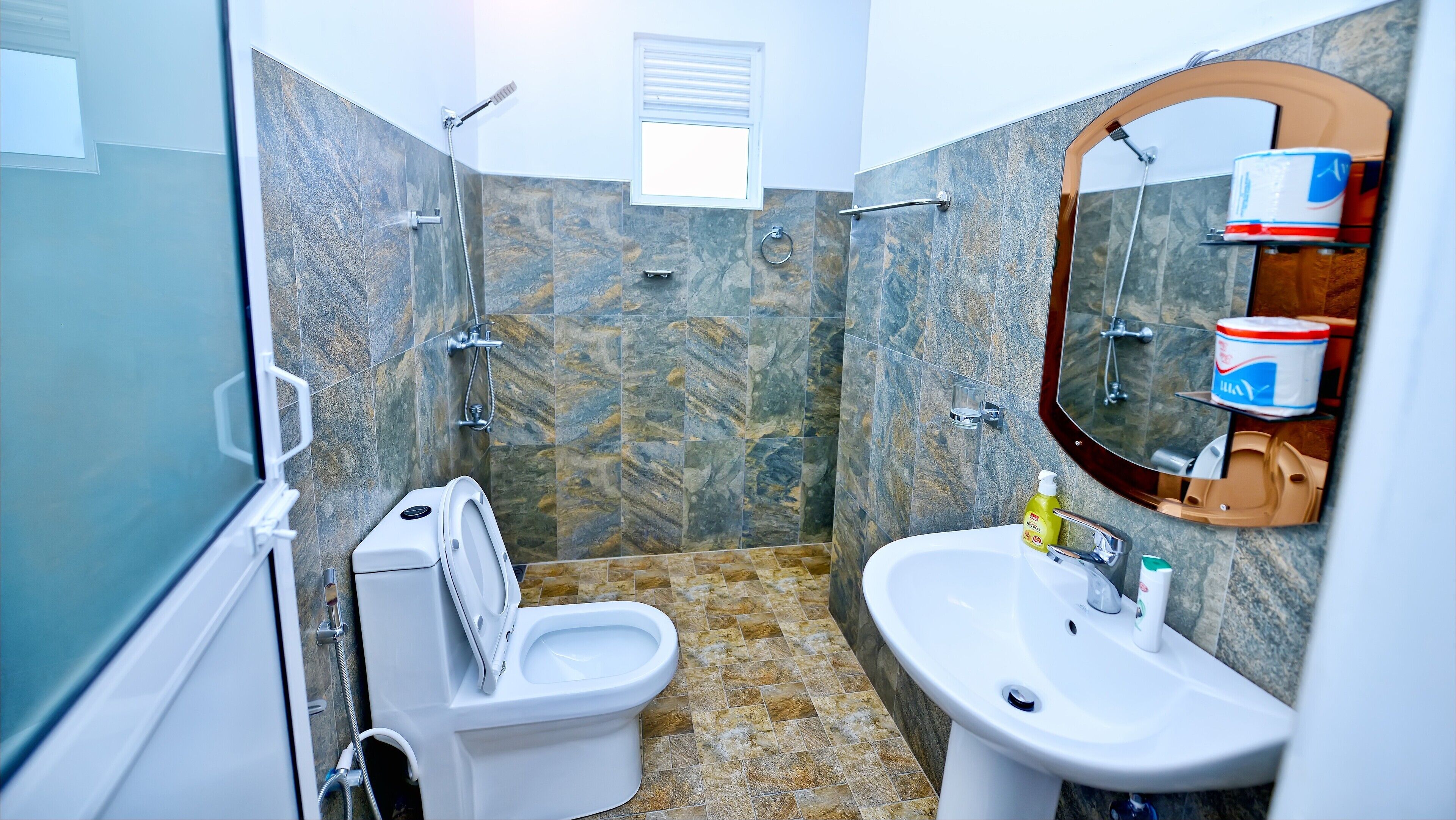 A bathroom with a toilet, bidet, shower, and sink.