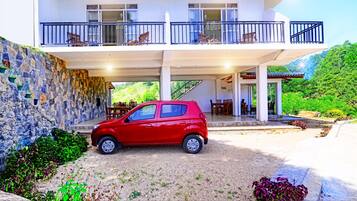 A two-story building with a stone facade, a red car parked in front, and outdoor seating areas.