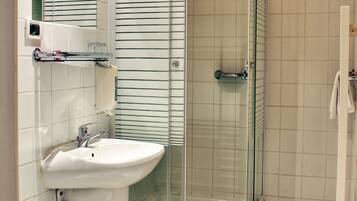 A bathroom with a glass-enclosed shower, a sink, and a toilet.