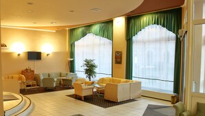 A hotel lobby with a seating area, a television, and a plant. - Hotel Centrál (Nagykanizsa)