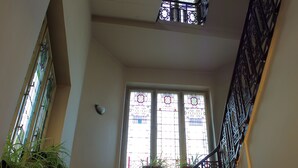 A staircase with a wrought iron railing, a large stained glass window, and a potted plant. - Hotel Centrál (Nagykanizsa)