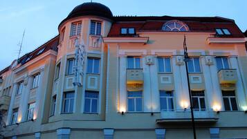 A multi-story building with a classical architectural style, featuring a prominent dome and a balcony with ornate railings.