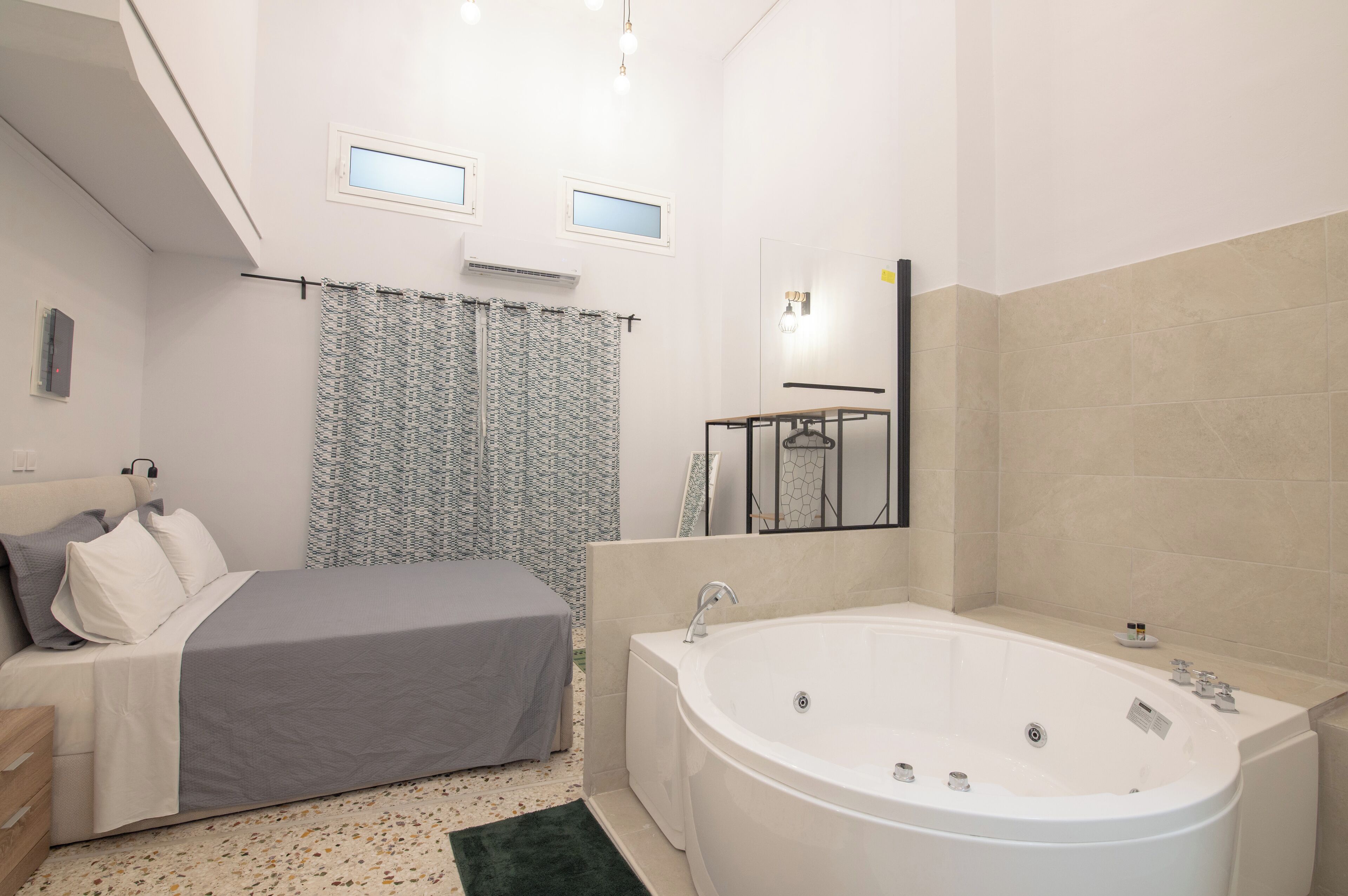 Une chambre à coucher moderne avec un grand lit, une salle de bain séparée avec une baignoire et une petite fenêtre.