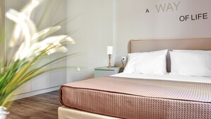 A neatly made bed with a textured pink bedspread, a bedside lamp, and a wall with the phrase "A WAY OF LIFE". - Athens Connection Apartments (Athens)