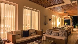 A spacious living area with a high ceiling, large windows, and a dining area. - Hacienda B-03 (Punta Cana)